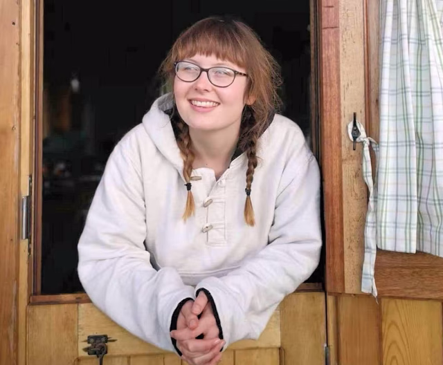 Image of Allie Mason leaning on a doorway and smiling