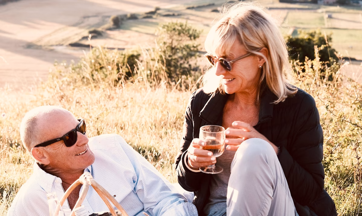 Image of sally Strang and her husband, Rob, enjoying a picnic on a grassy slope