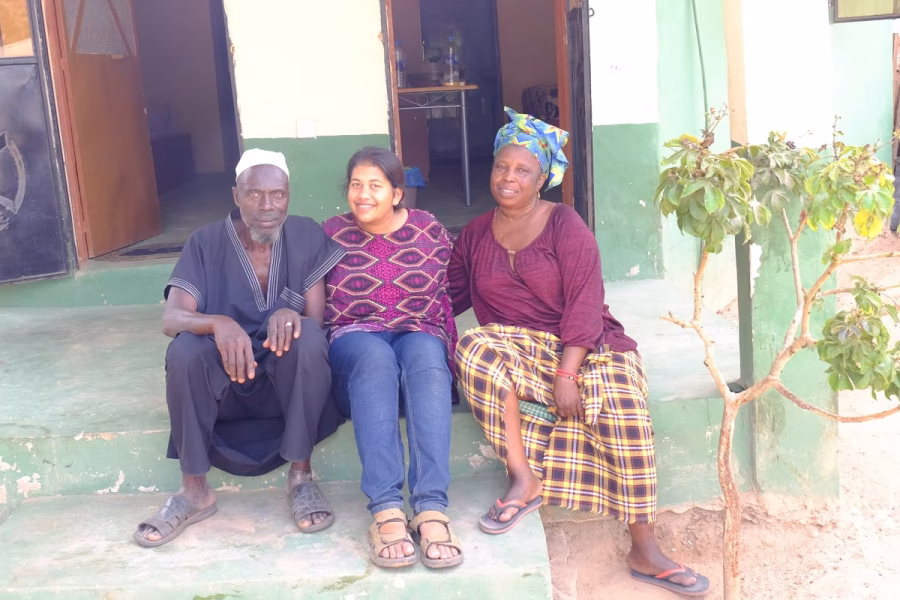 Jayni Gudka sitting outside a house with two villagers