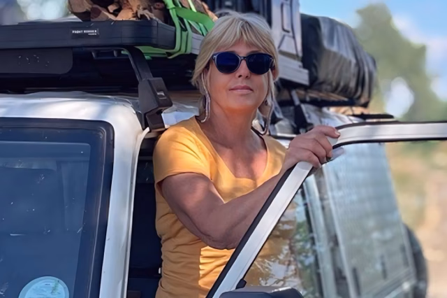 Image shows Clare Minchin stood in the open doorway of a safari vehicle