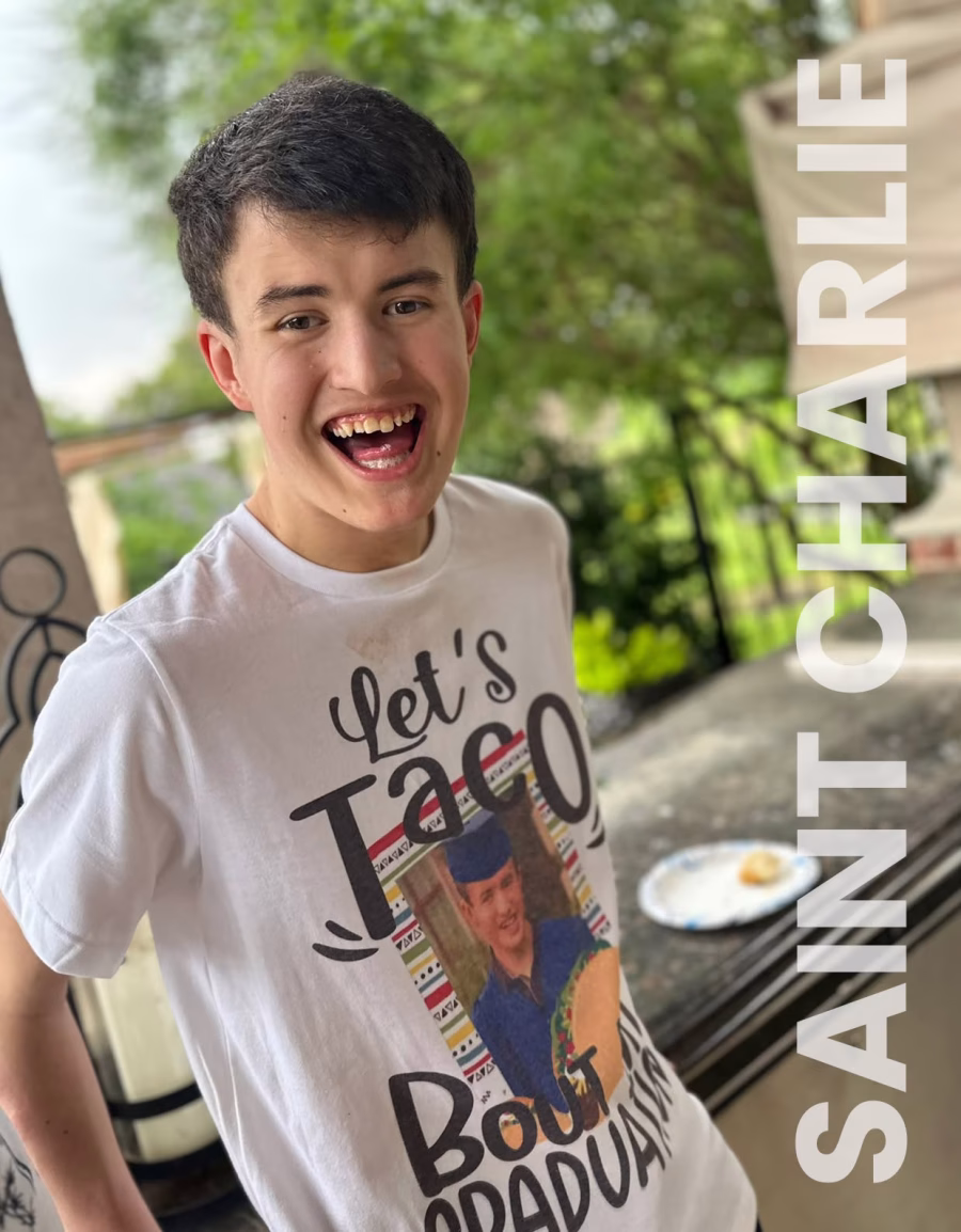 Image shows a smiling Charlie wearing a white t-shirt with 'Let's Taco' motif.