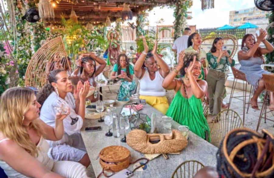 A group of guests enjoy an Impulse Travel event. Some are seated around a table in a roadside restaurant.